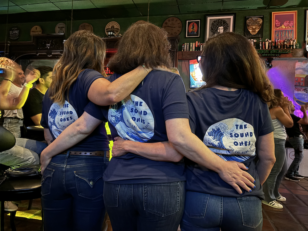 Three beautiful women wearing the band t-shirts from the back